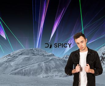 Ein junger Mann steht vor einer futuristischen Landschaft mit bunten Lichtern im Hintergrund. Der Schriftzug "DJ SPICY" ist sichtbar.