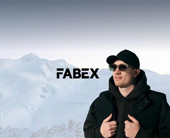 Ein Mann steht vor einer schneebedeckten Berglandschaft und trägt Sonnenbrillen. Im Hintergrund ist der Schriftzug "FABEX" zu sehen.