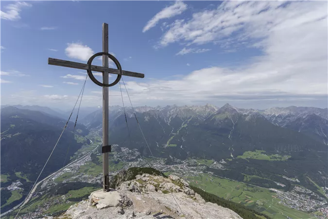 Ein typisches Haus in einer natürlichen Umgebung mit Felsen im Hintergrund. Der Bereich ist grün und von Bäumen umgeben.
