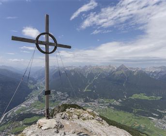 Ein typisches Haus in einer natürlichen Umgebung mit Felsen im Hintergrund. Der Bereich ist grün und von Bäumen umgeben.