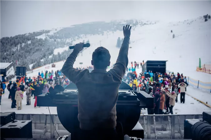 A DJ is standing on the large open-air stage in the Hochzeiger ski area at an altitude of 2,000 meters.