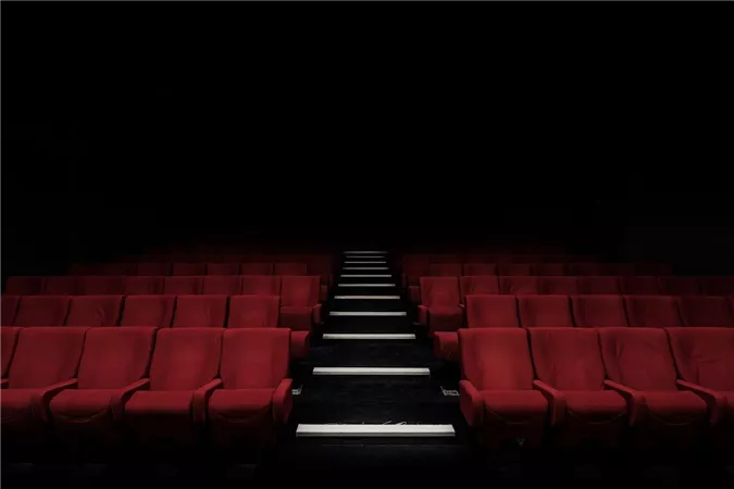 A dark cinema with red seats. The path in the middle is well lit.