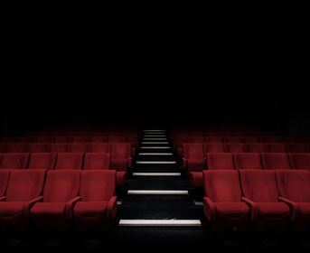 A dark cinema with red seats. The path in the middle is well lit.