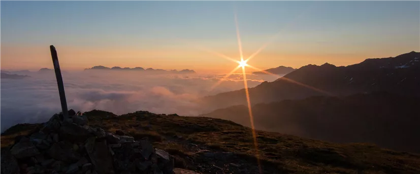 Ein atemberaubender Sonnenaufgang über den Bergen. Die Aussicht ist von Nebel und sanften Hügeln umgeben.