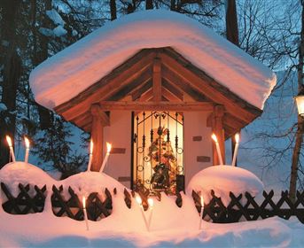 Ein hübsches Hütchen, das unter einer dicken Schicht Schnee steht. Fackeln beleuchten den Eingang und schaffen eine gemütliche Atmosphäre.