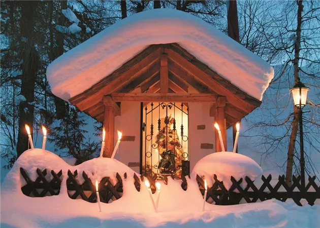 Ein hübsches Hütchen, das unter einer dicken Schicht Schnee steht. Fackeln beleuchten den Eingang und schaffen eine gemütliche Atmosphäre.