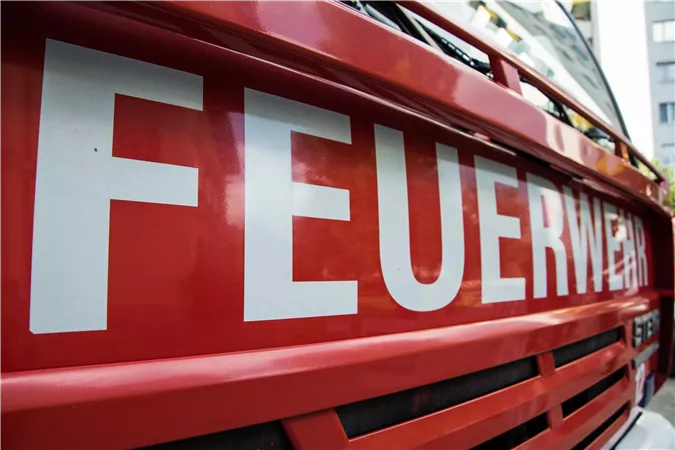 Ein Feuerwehrfahrzeug mit der Aufschrift "FEUERWEHR". Die leuchtend rote Farbe ist prägnant und auffällig.