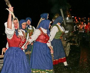 Grouping of people in traditional costumes, creating a festive atmosphere. They seem to be participating in a nighttime parade or celebration.