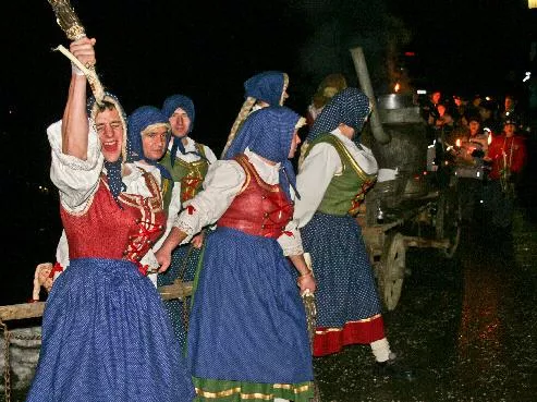 Gruppierung von Menschen in traditionellen Kostümen, die eine feierliche Atmosphäre schaffen. Sie scheinen an einem nächtlichen Umzug oder Fest teilzunehmen.