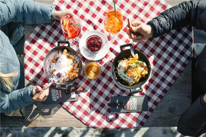 Eine stilvolle Tischdekoration mit roten und weißen Karos. Zwei Personen genießen köstliche Gerichte und Getränke in einer einladenden Atmosphäre.