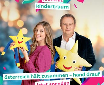 Zwei Personen halten fröhliche Stern-Kissen in der Hand. Im Hintergrund leuchten bunte Dekorationen, und es steht der Text „Österreich hält zusammen – Hand drauf, jetzt spenden“.
