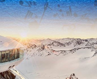 Ein modernes Gebäude mit Rundungen in der schneebedeckten Berglandschaft. Die Sonne geht hinter den Bergen auf und verbreitet eine warme Atmosphäre.