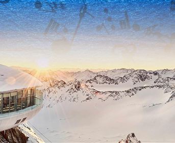 Ein modernes Gebäude mit Rundungen in der schneebedeckten Berglandschaft. Die Sonne geht hinter den Bergen auf und verbreitet eine warme Atmosphäre.