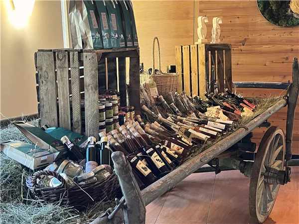 Ein rustikaler Wagen aus Holz voller Gläser und Flaschen mit verschiedenen Lebensmitteln und Getränken. Die Präsentation wirkt einladend und authentisch.