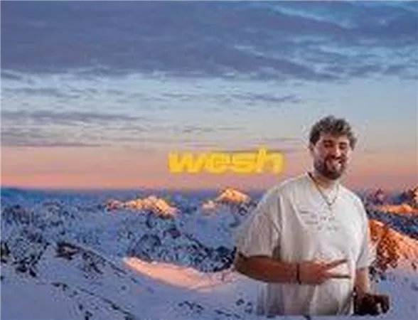 Ein Mann steht lächelnd vor einer verschneiten Berglandschaft. Der Himmel ist in warmen Farben während des Sonnenuntergangs gefärbt.