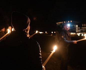 A winter landscape with snow-covered mountains and a clear blue sky. Footprints lead through the fresh snow.