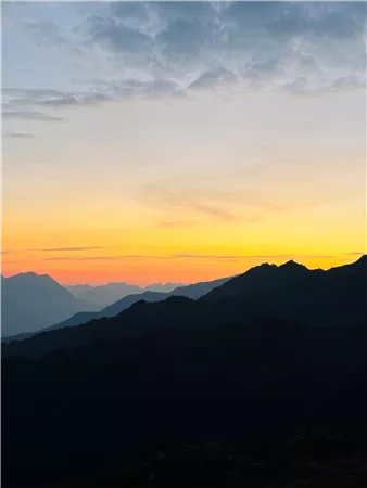 Ein atemberaubender Sonnenuntergang über den Bergen. Die Silhouetten der Berge sind gegen den leuchtenden Himmel sichtbar.