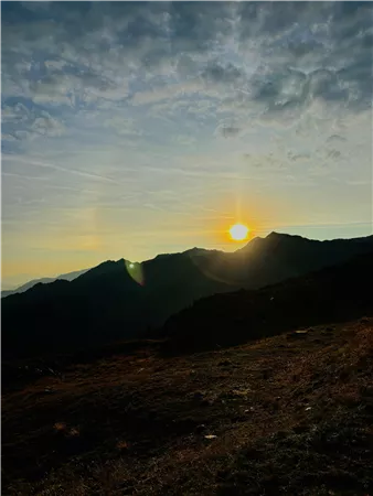Ein atemberaubender Sonnenuntergang über den Bergen. Die Landschaft ist ruhig und die Wolken sind sanft beleuchtet.