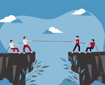 Four people are pulling on a rope that's stretched between two cliffs. The sky is blue with some clouds, and there are plants in the foreground.