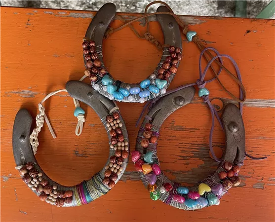 Three creative pieces of jewelry made from wood and colorful beads lie on an orange surface. Each piece has a unique design and combines different materials and colors.
