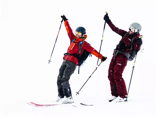 Zwei Skifahrer haben Spaß im Schnee. Sie tragen bunte Skibekleidung und genießen die winterliche Landschaft.