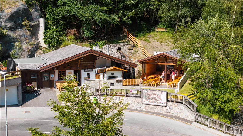 A rustic building with a terrace amidst a green environment. Guests enjoy the outdoor atmosphere.