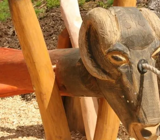 A wooden sculpture in the shape of an animal head is visible in the picture. The artwork displays a mix of natural wood and carved details.