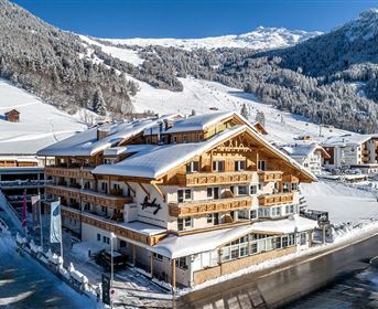 Ein gemütliches Hotel in den Alpen, umgeben von schneebedeckten Bergen. Die klare, kalte Winterluft schafft eine malerische Atmosphäre.