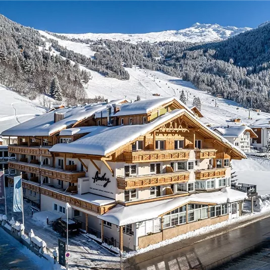 Ein gemütliches Hotel in den Alpen, umgeben von schneebedeckten Bergen. Die klare, kalte Winterluft schafft eine malerische Atmosphäre.