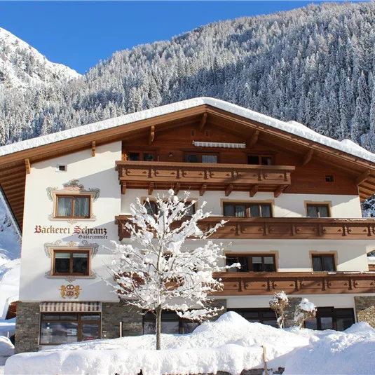 Ein charmantes Chalet in den Bergen, umgeben von Schnee. Die Fassade ist traditionell gestaltet und strahlt eine einladende Atmosphäre aus.
