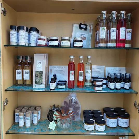 Ein Verkaufsregal mit verschiedenen Gläsern und Flaschen. Die Produkte umfassen Marmelade, Sirupe und Gewürze.