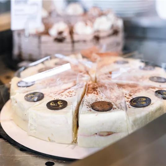 A delicious cake with a creamy layer and decorative toppings. It is cut into pieces and stands on a table.