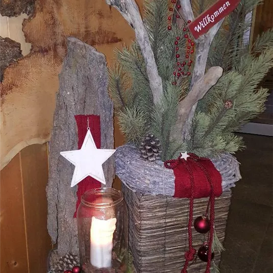 A festive decoration with sprigs of fir, candles, and a white star. The elements are harmoniously arranged, creating a cozy Christmas atmosphere.