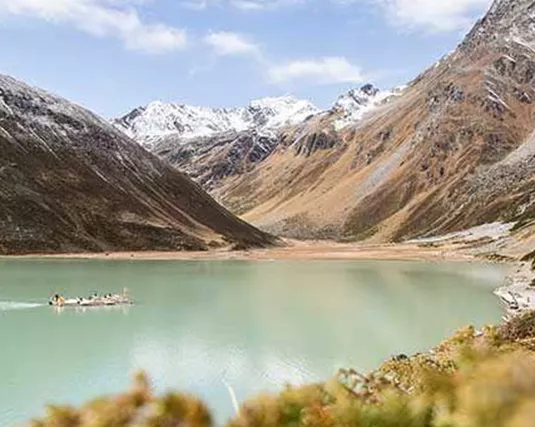 Ein ruhiger Bergsee umgeben von majestätischen Bergen mit schneebedeckten Gipfeln. Das klare Wasser spiegelt die Natur wider.