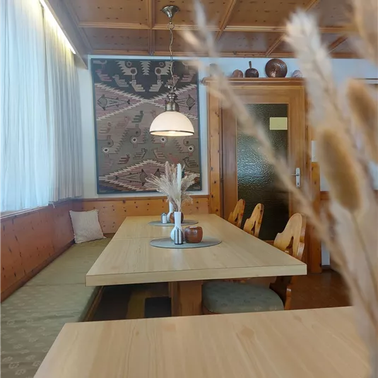 A cozy dining area with wooden tables and an inviting atmosphere. The walls are tastefully decorated, and the room is well lit.