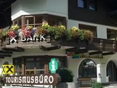 A traditional building with a balcony and floral decoration. It houses a tourist office and a Raiffeisen bank.
