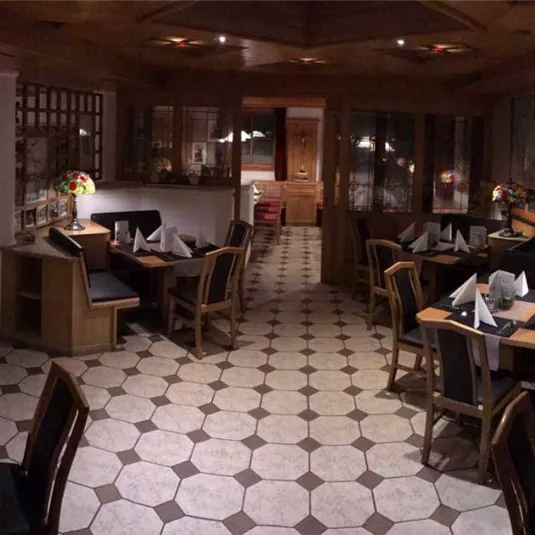 A cozy restaurant with wooden interiors and elegant lamps. The tables are set for guests and invitingly decorated.