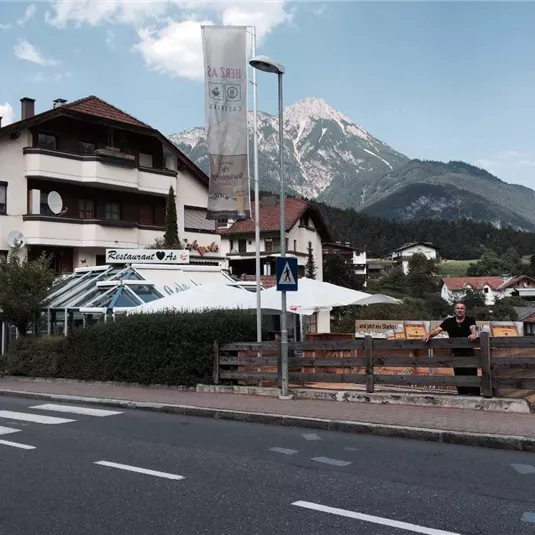 A picturesque restaurant with a covered terrace and an impressive mountain in the background. The surroundings are quiet and rural, perfect for a relaxing stay.