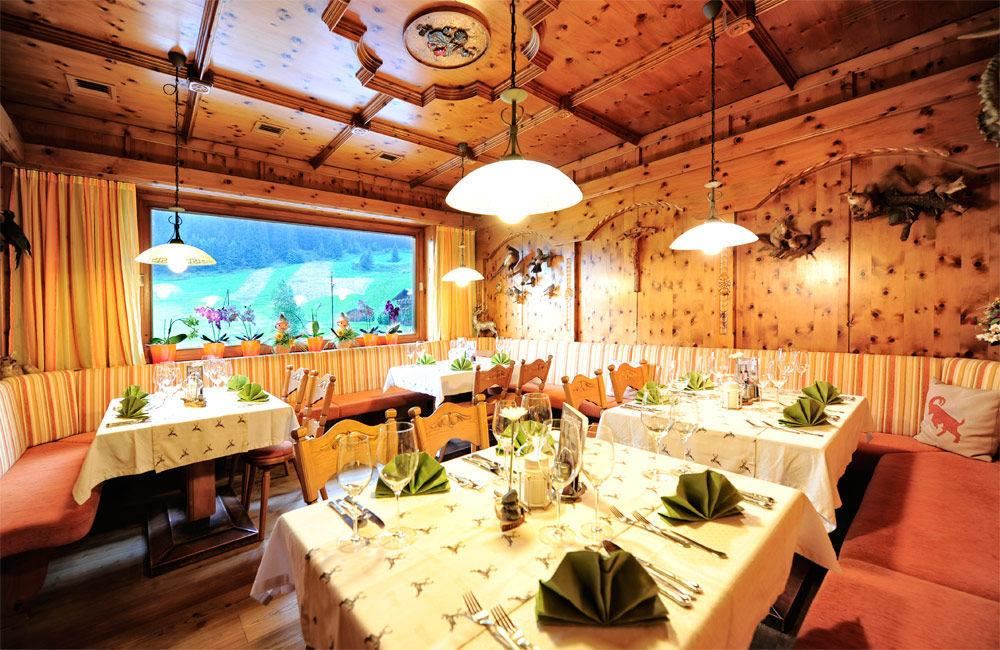 Ein gemütliches Restaurant mit Holzverkleidung und warmem Licht. Die Tische sind schön gedeckt und bieten einen Blick auf die natürliche Umgebung.