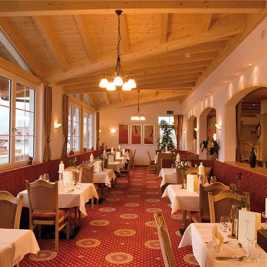 Ein elegantes Restaurant mit Holzdecke und einladendem Ambiente. Die Tische sind geschmackvoll gedeckt und es gibt große Fenster mit Ausblick.