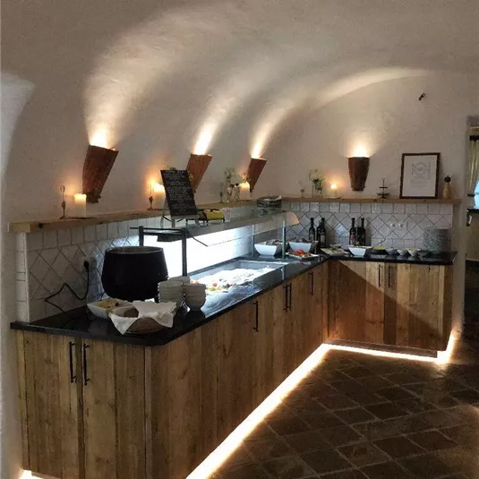 Eine moderne Küche mit Holzschränken und elegantem Licht. Der Raum hat eine gemütliche Atmosphäre und ist gut ausgestattet.