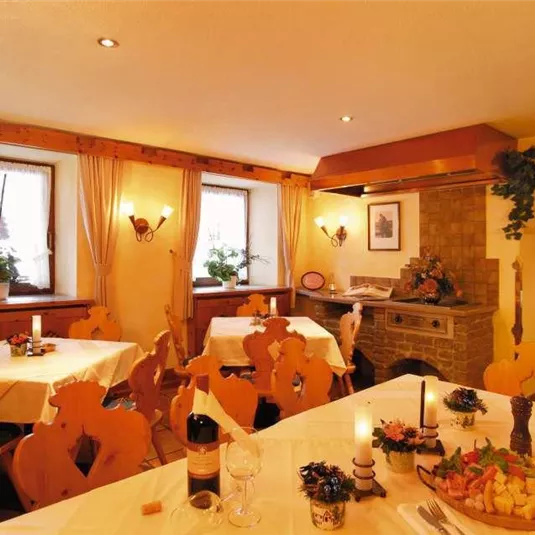 Ein gemütliches Restaurant mit Holzdekor und Tischgedecken. Die Fenster lassen sanftes Licht herein und bieten eine warme Atmosphäre.
