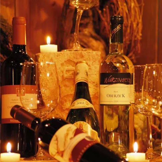 Eine stilvolle Anordnung von Weinen und Gläsern auf einem rustikalen Tisch. Kerzenlicht sorgt für eine gemütliche Atmosphäre.