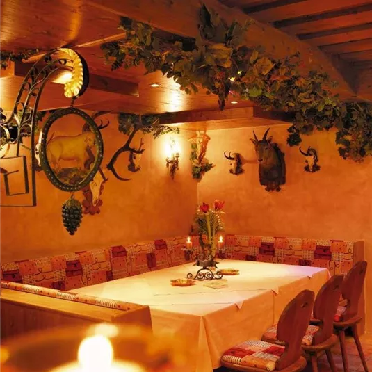 Ein gemütliches Restaurant mit Holzdecke und warmem Licht. Der Tisch ist festlich gedeckt und von dekorativen Wandstücken umgeben.