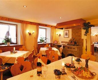 Ein gemütliches Restaurant mit Holzstühlen und weißen Tischdecken. Auf den Tischen stehen Wein und frische Speisen.