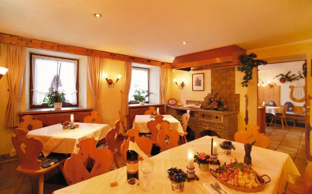 Ein gemütliches Restaurant mit Holzstühlen und weißen Tischdecken. Auf den Tischen stehen Wein und frische Speisen.