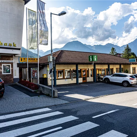 A small building with a shop in a quiet town. In the background, mountains and a clear sky can be seen.