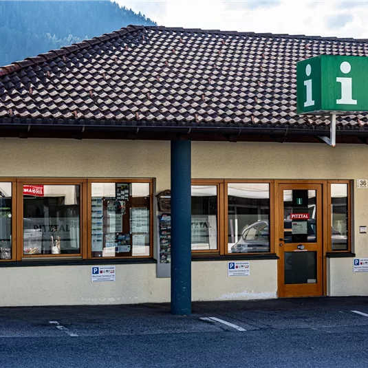 An information center with a greened roof and large windows. The sign above the entrance displays an "i" for information.