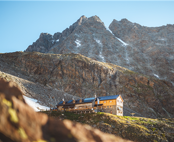 Ein charmantes Berghaus, umgeben von majestätischen Bergen. Die Landschaft ist klar und einladend.