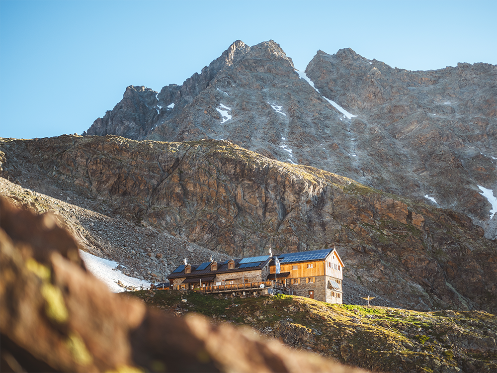 Ein charmantes Berghaus, umgeben von majestätischen Bergen. Die Landschaft ist klar und einladend.